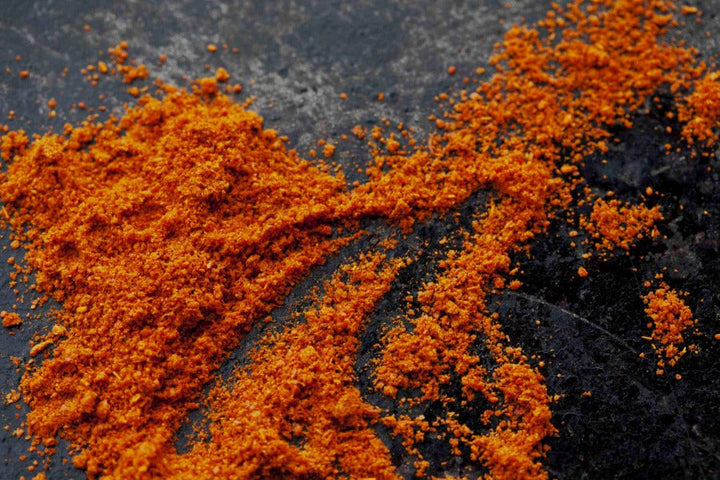 Loose orange-red cayenne pepper powder in close-up, textured mound