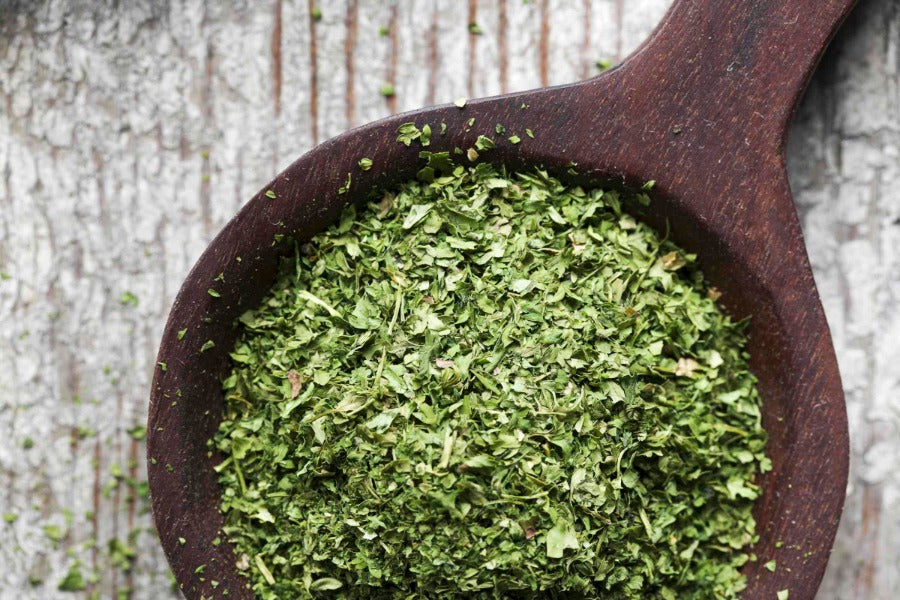 Chervil herb flakes in wooden spoon, finely chopped green seasoning