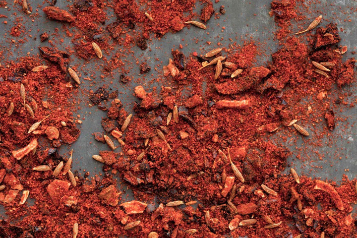Ground ancho chili powder with red flakes and small seed pieces