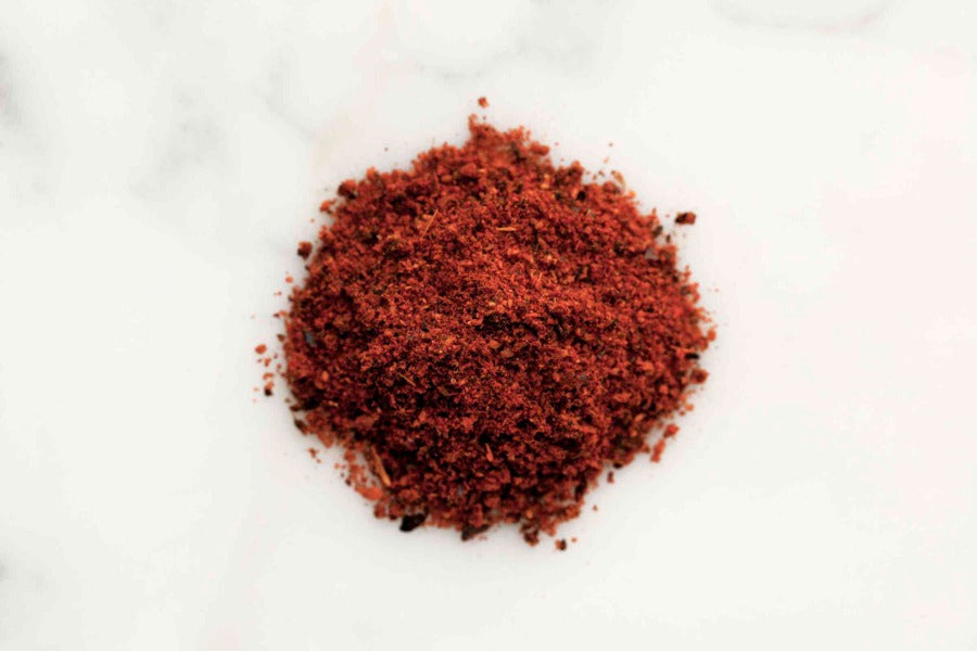 Chipotle chili powder pile of finely ground red spice granules on a white background