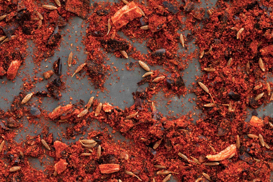 Ground red chili powder with scattered chili flakes, loose on the surface.