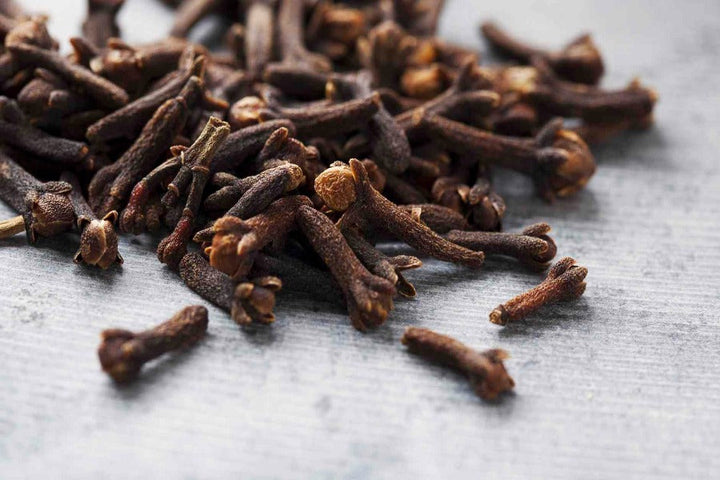 Whole cloves on light surface, brown dried clove buds