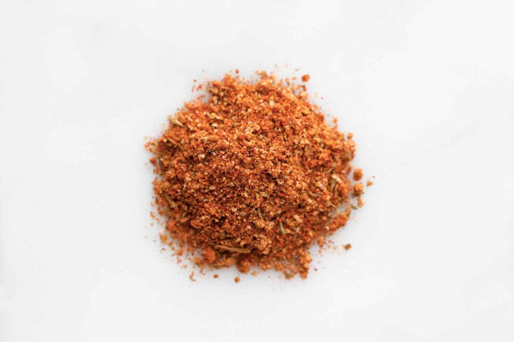 Heap of finely ground red-brown Creole spice seasoning on a light surface