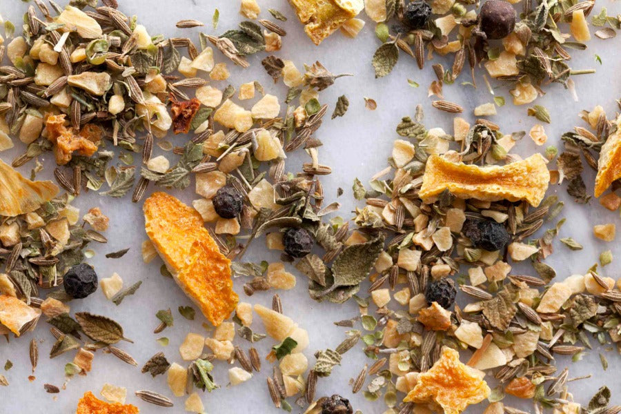 Whole spice mix with leaves, berries, and crushed pepper on a flat surface