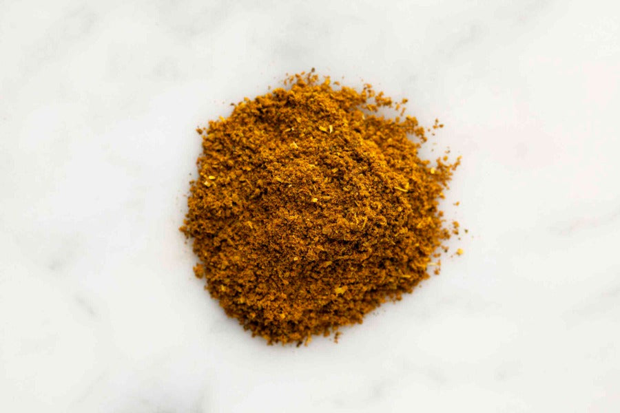 Ground curry spice powder mound in an orange-brown tone