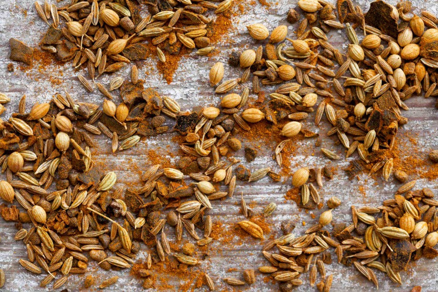 Kashmiri curry seasoning with whole spice seeds scattered on a flat surface