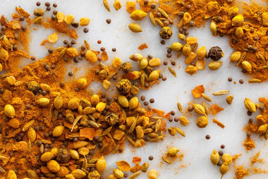 Yellow-orange South Indian curry spice blend with scattered seeds and flakes