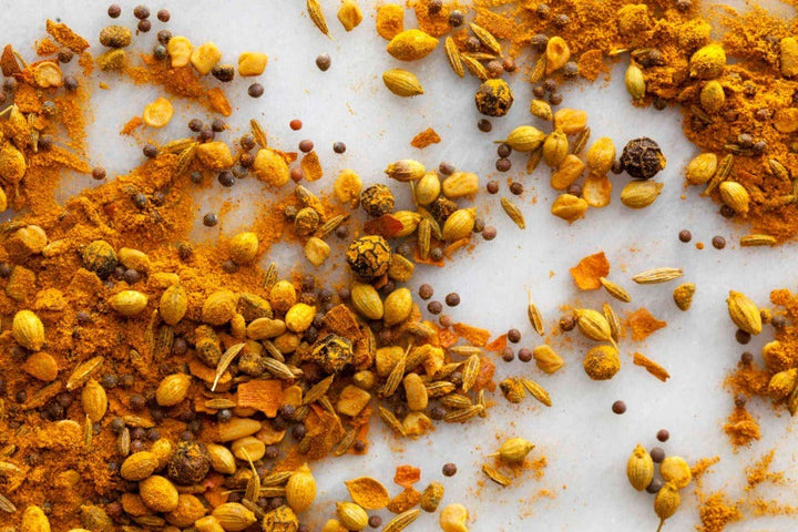 Yellow-orange South Indian curry spice blend with scattered seeds and flakes