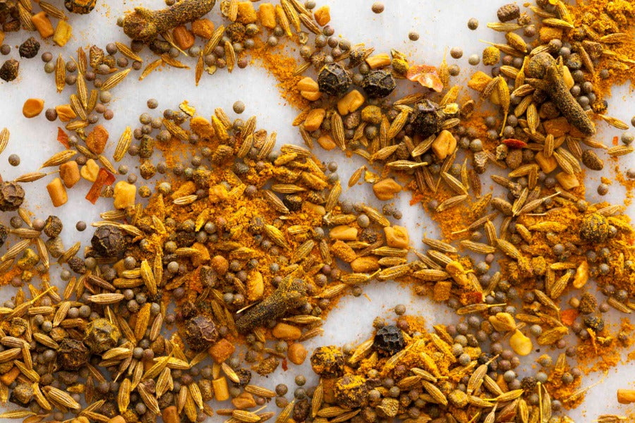 Vadouvan curry spice blend with ground spices and small whole pieces, scattered