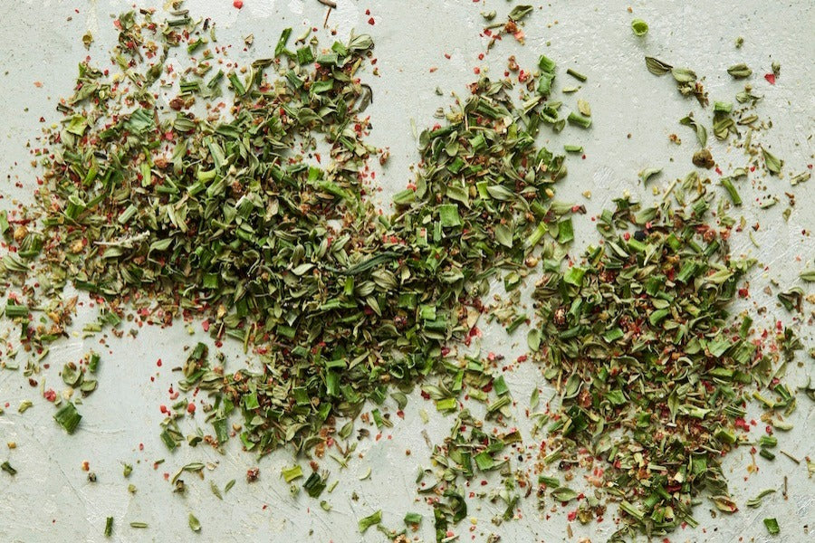 Chopped herbal seasoning blend spread on a light surface.