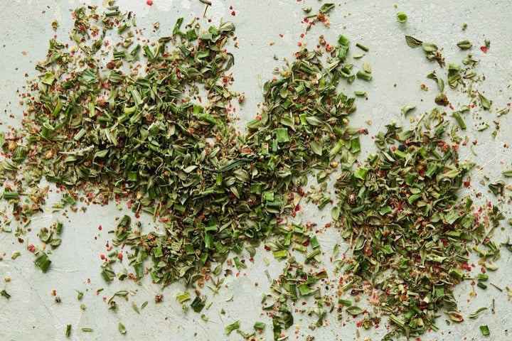 Chopped herbal seasoning blend spread on a light surface.