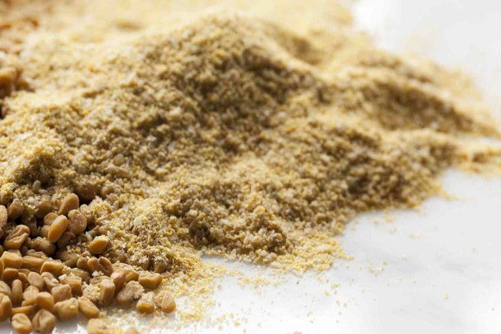 Ground fenugreek seed powder, fine golden-brown spice dust.