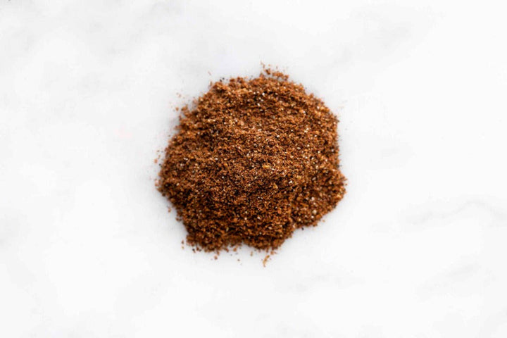 Ground garam masala powder, dark brown spice blend in a small pile
