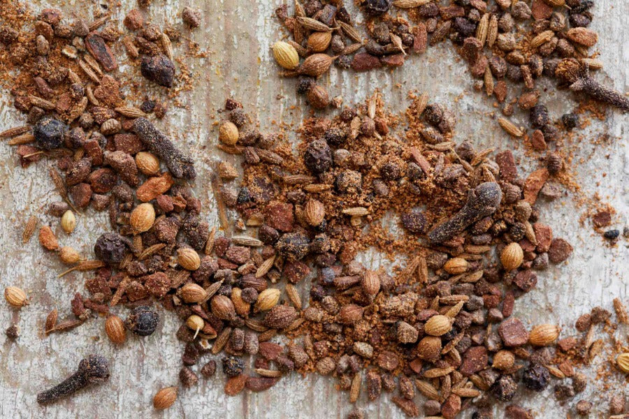 Garam masala spice blend with whole spices and seeds, scattered on a surface