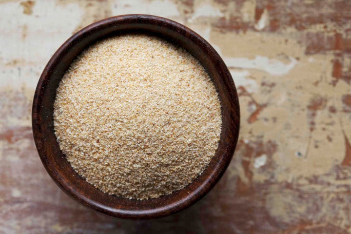Garlic granules in a small brown bowl, fine beige powder