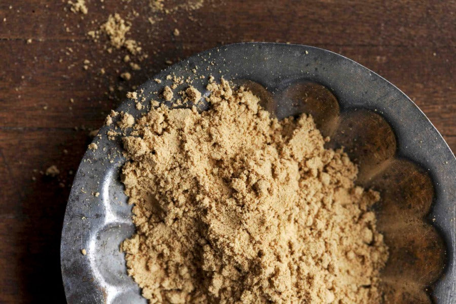 Ginger powder in a metal spoon, loose light-brown powder