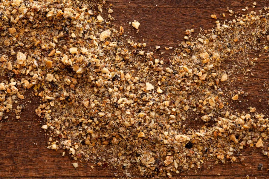 Spice blend granules in brown and gold with garlic-pepper texture on wood