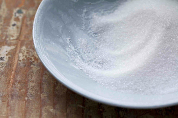 Citric acid powder in a white bowl, fine granules