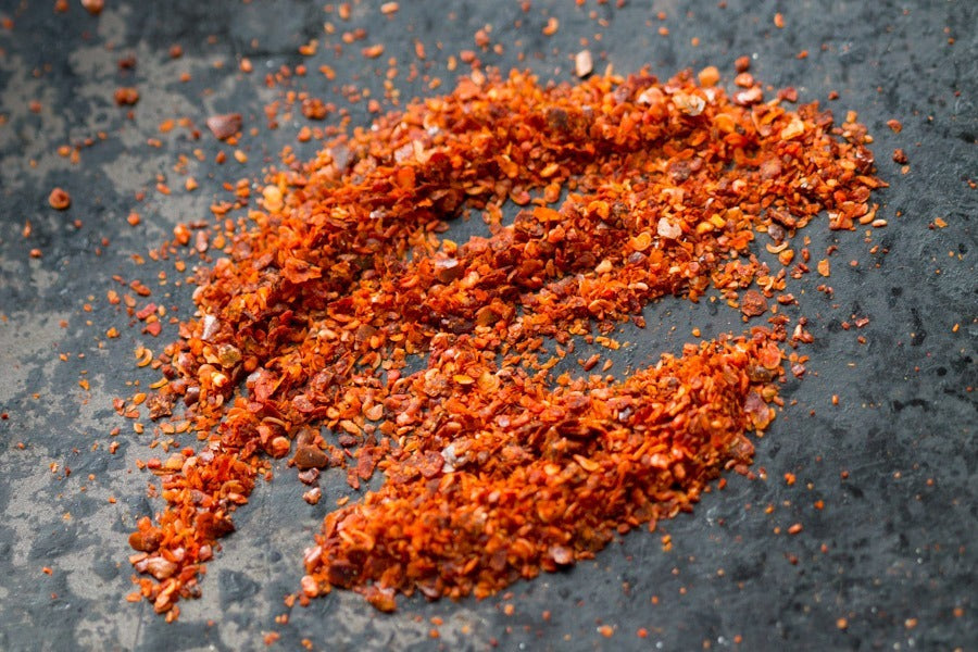 Marash chile flake seasoning, finely crushed red-orange flakes in a mound