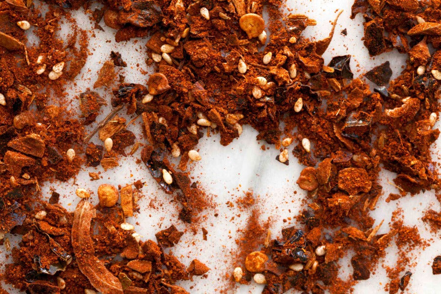 Ground reddish-brown mole seasoning with seeds and spice flakes