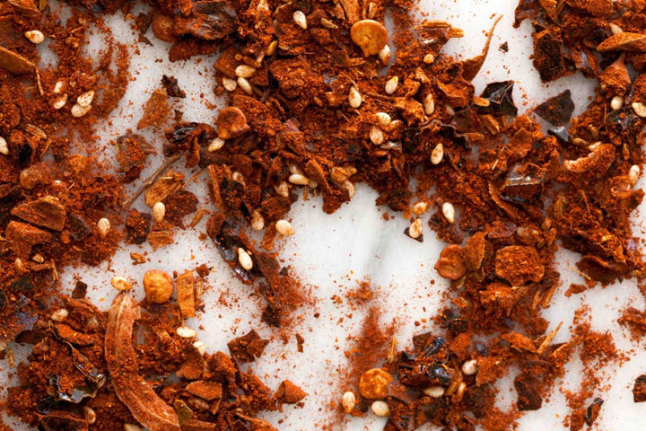 Ground reddish-brown mole seasoning with seeds and spice flakes