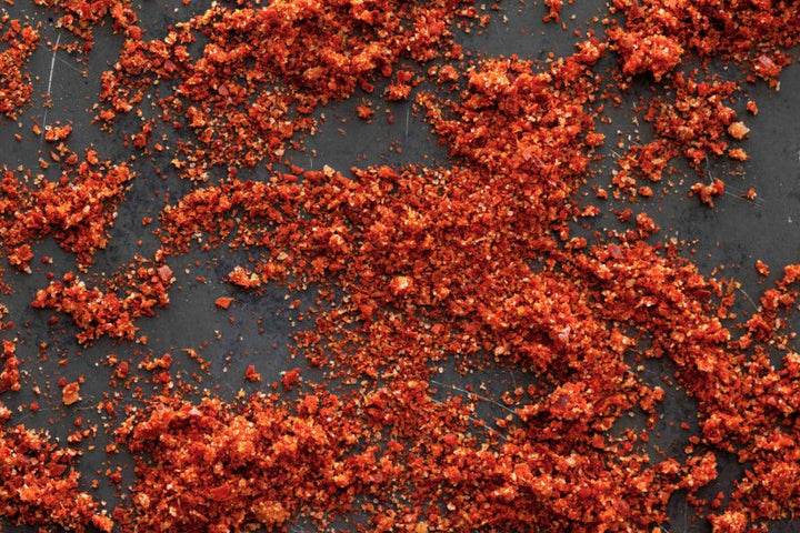 Red spice flakes blend scattered on a dark surface