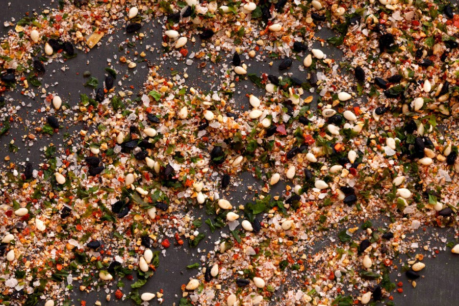 Seasoned salt spice blend with herbs and flakes scattered on a dark surface