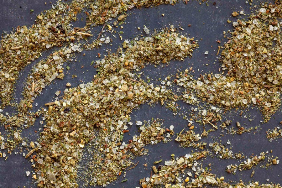 Seasoned salt blend with green herb flakes and pepper bits, scattered on surface