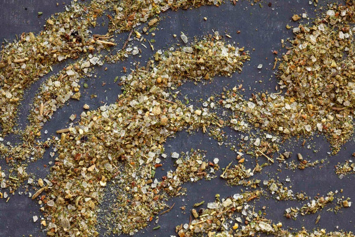 Seasoned salt blend with green herb flakes and pepper bits, scattered on surface