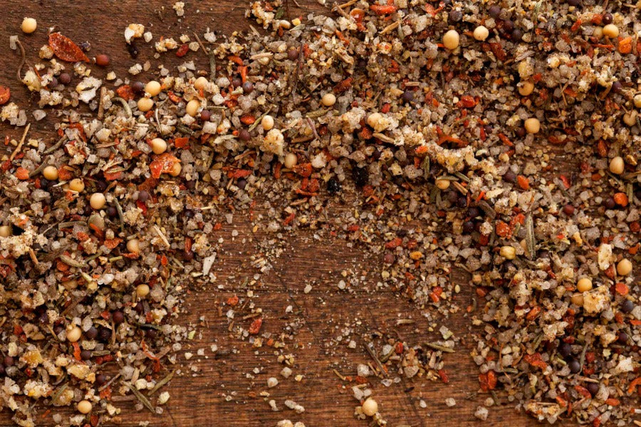 Voodoo spice mix scattered on wooden board, multicolored ground herbs and pepper