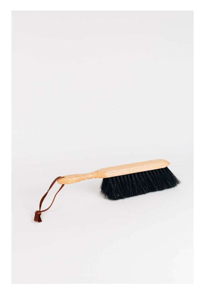Wood dustbrush with dark bristles, wooden handle and leather hanging loop