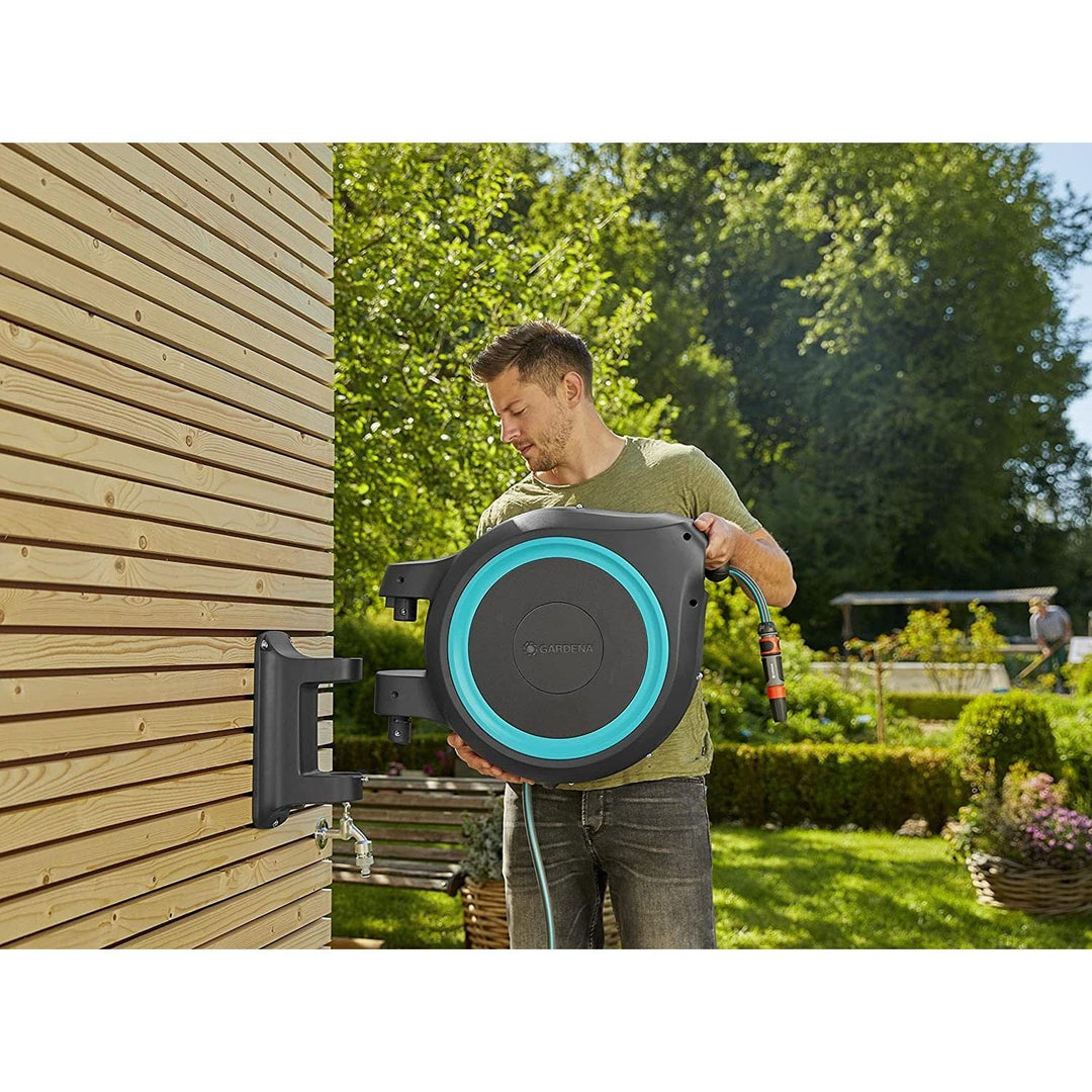 Wall-mounted hose reel with blue-ring face, connected hose, and spray nozzle
