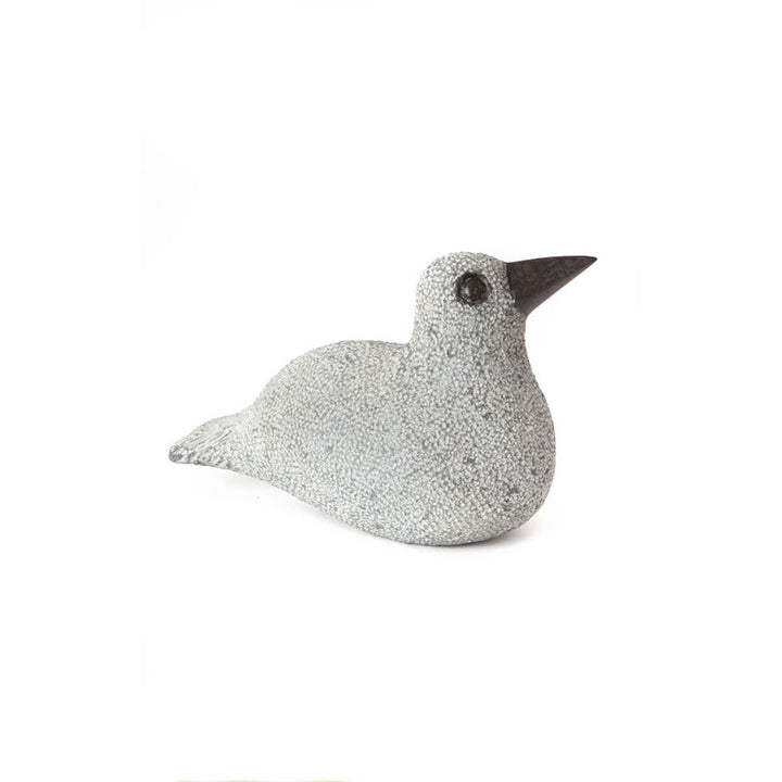 Stone duck sculpture lying down, speckled light gray body with dark beak and eye