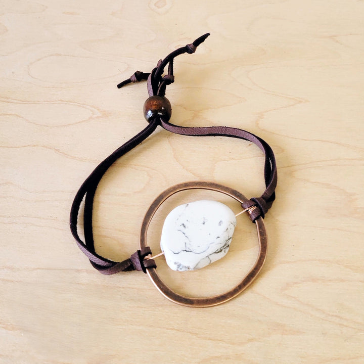 Adjustable tie bracelet with black cord and round metal ring set with white marble stone