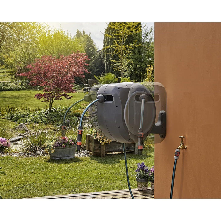Outdoor retractable hose reel mounted on wall with coiled hose and hose nozzle