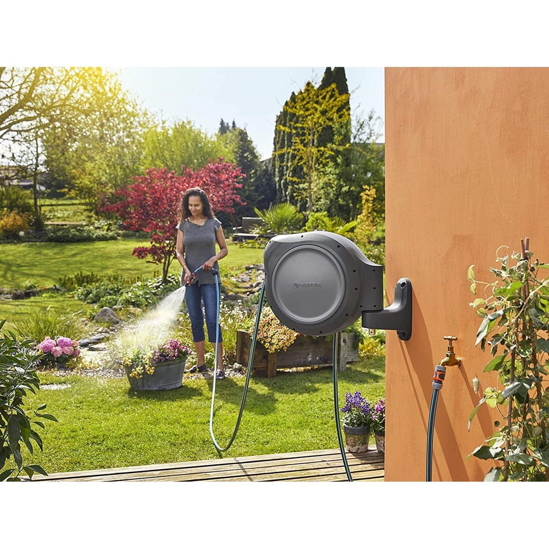 Retractable hose reel mounted on wall with coiled hose and connected faucet