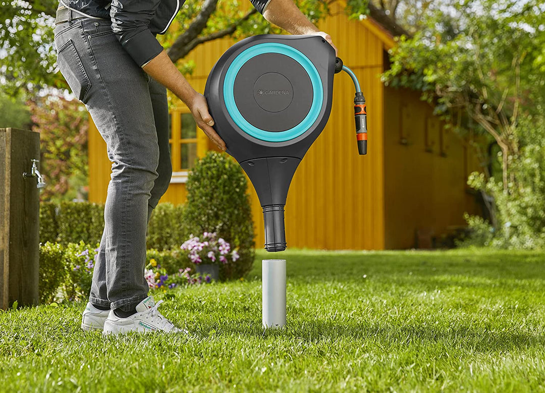 Roll-up garden hose reel standing on grass with blue ring and hose connected