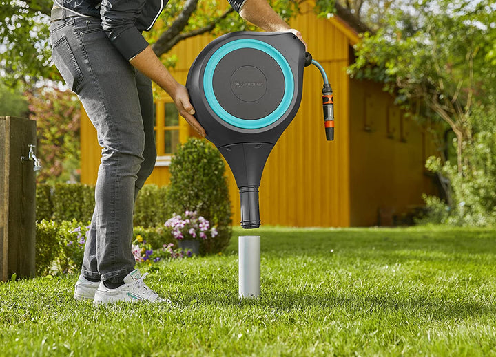 Roll-up garden hose reel standing on grass with blue ring and hose connected