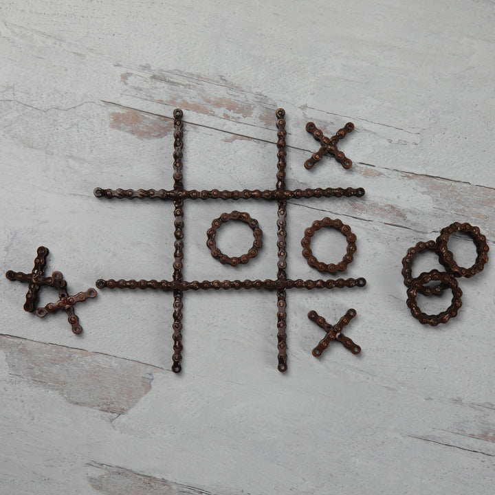 Recycled chain-link tic-tac-toe pieces laid out: X crosses, O rings, and grid bars.