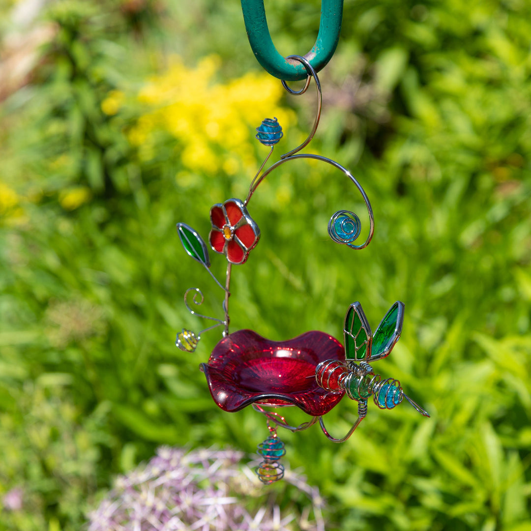 Stained glass hummingbird feeder ornament with red body, green wings, and blue flower details.