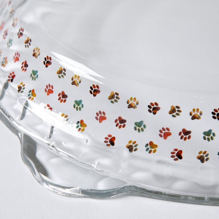 Clear glass pie plate with colorful paw-print pattern on the bowl