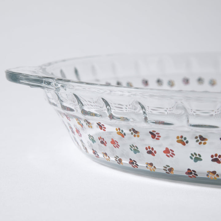Clear glass pie plate with colorful paw-print decoration along the rim