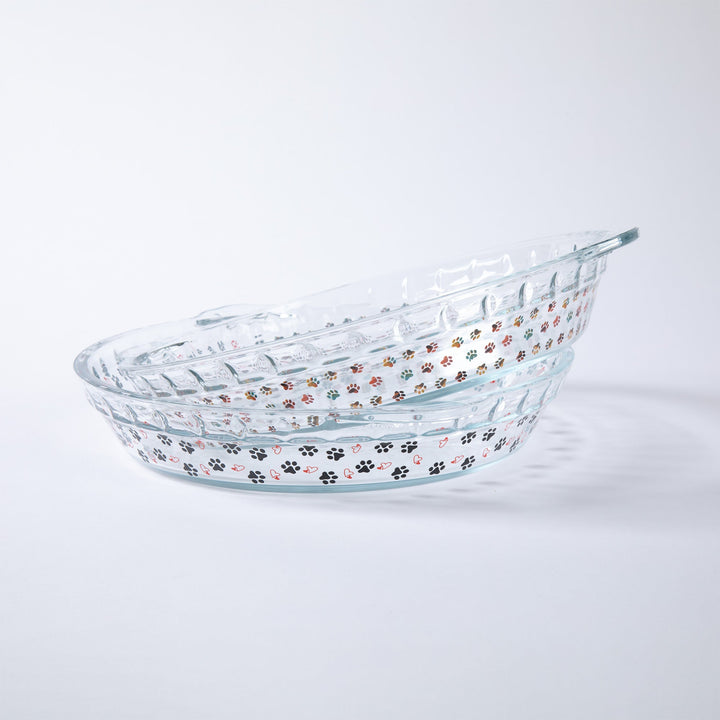 Clear glass pie plate with colorful paw-print pattern and oval shape