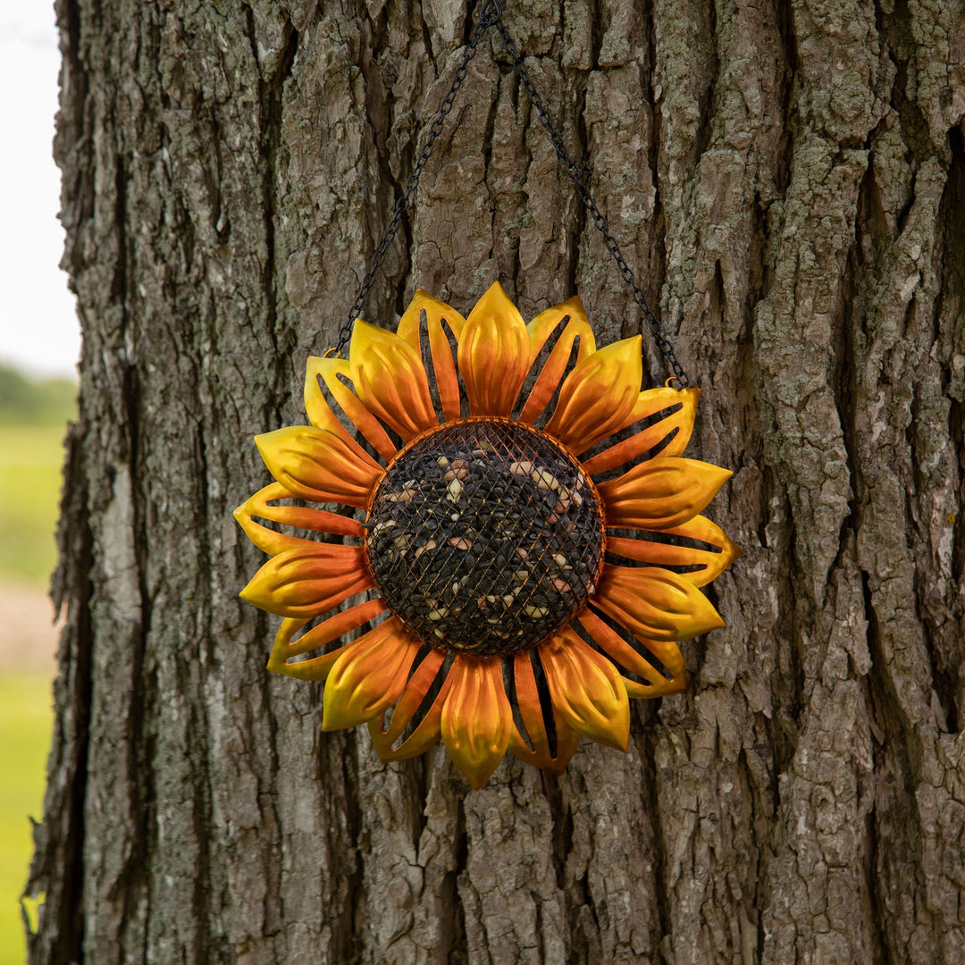 Hanging sunflower mesh bird feeder on a tree, yellow-gold petals with dark mesh center