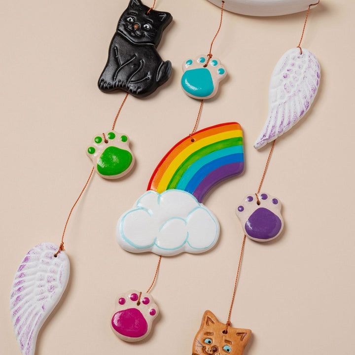 Ceramic pet memorial wind chime close-up of rainbow, cloud, wings, and paw-print charms