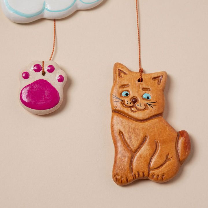 Ceramic pet memorial wind chime close-up of pink paw ornament and orange cat ornament