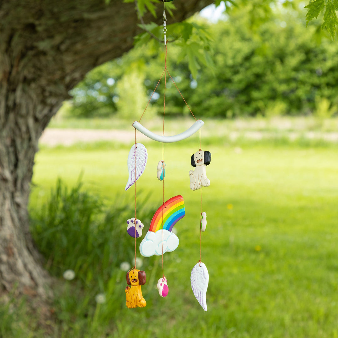 Ceramic pet memorial wind chime outdoors with rainbow, cloud, wings, and dog-and-cat charms