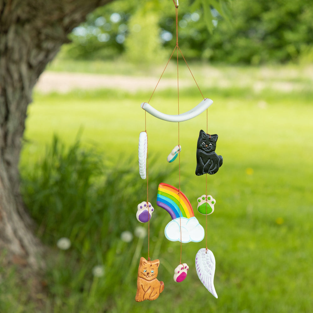 Ceramic pet memorial wind chime hanging from branch with rainbow, cloud, wings, and cat