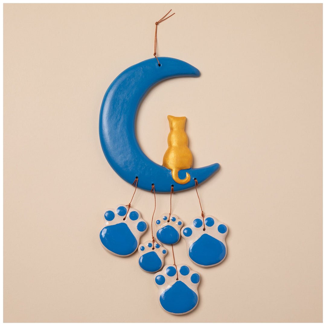 Ceramic moon wind chime with blue paw ornaments and a gold cat figurine at the center