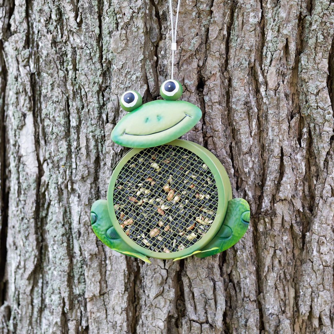 Green frog hanging bird feeder mounted on tree with round mesh basket
